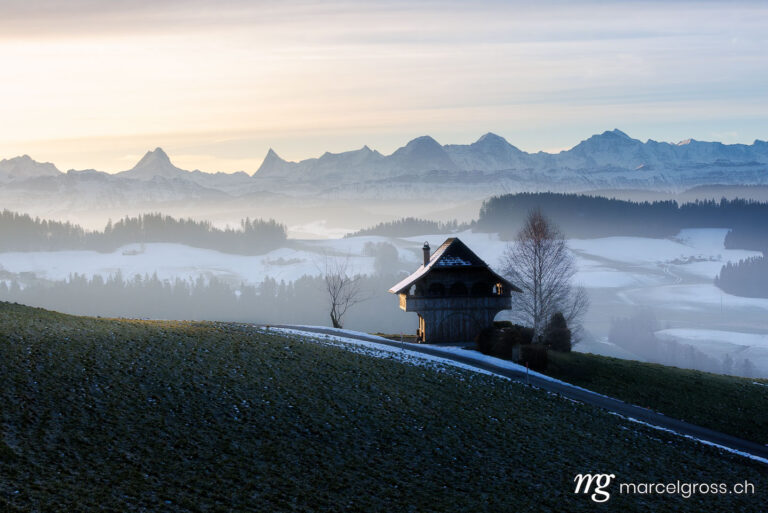 Emmental winter pictures. Emmentaler Spycher in winter in front of the Bernese Alps. Marcel Gross Photography