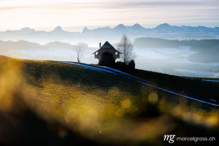 Emmental winter pictures. Emmentaler Spycher in winter in front of the Bernese Alps. Marcel Gross Photography